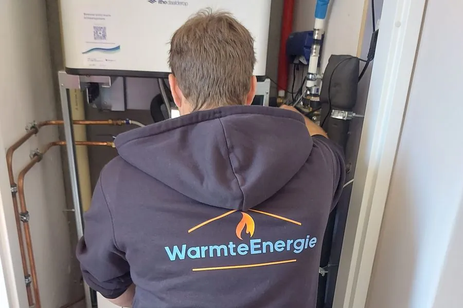 Het WarmteEnergie-logo op de werkkleding van de monteur