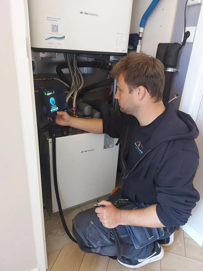 Monteur van Warmte Energie meet rookgassen bij een warmtepomp